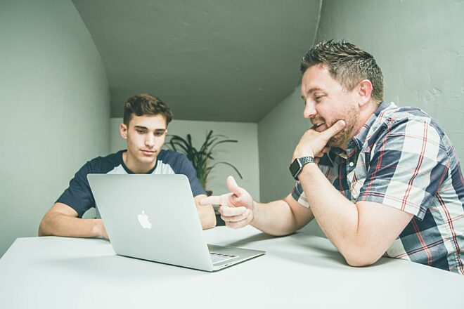 Jongen met oudere man in gesprek met laptop